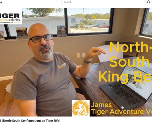 Video thumbnail: man at a table in an office discussing a North-South King Bed configuration for Tiger Adventure Vehicles.