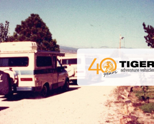 Vintage camper van on a dirt road with trees; translucent overlay reads '40 years' with a tiger logo and 'TIGER adventure vehicles'.