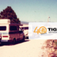 Vintage camper van on a dirt road with trees; translucent overlay reads '40 years' with a tiger logo and 'TIGER adventure vehicles'.