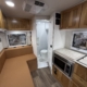 Interior of a compact RV: brown leather seating, wooden cabinets, and a marble-look countertop with a microwave/oven unit.