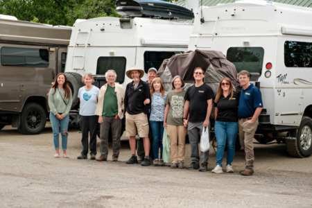 Vermejo-tiger-adventures-1 | Tiger Adventure Vehicles Group of people standing in a parking lot beside large campers, posing for a photo and smiling at the camera.