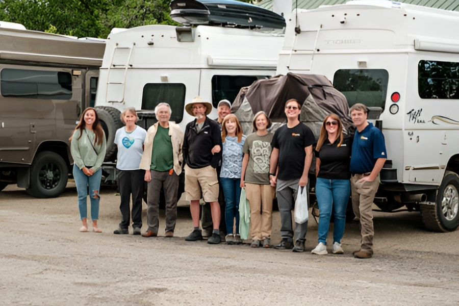 Vermejo-tiger-adventures-1 | Tiger Adventure Vehicles | Tiger Adventure Vehicles Group of people standing in a parking lot beside large campers, posing for a photo and smiling at the camera.