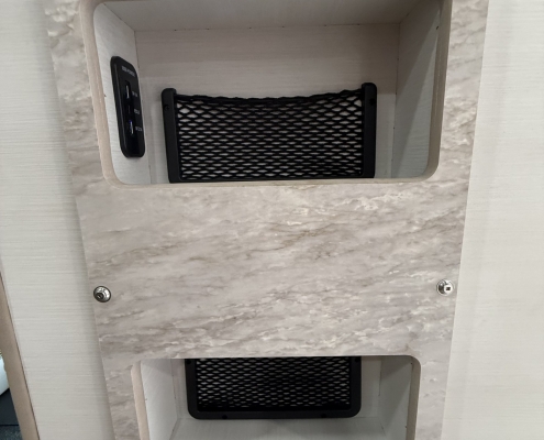 7d1f725d-d25c-46c0-8279-838d33ae3546 | Tiger Adventure Vehicles Two rectangular recessed storage slots with black mesh nets in a marble-patterned panel.