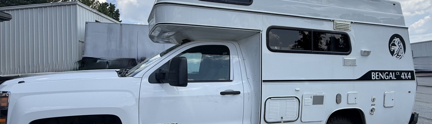e9e22218-4741-43a0-b141-a047e8d4af3f | Tiger Adventure Vehicles White class-C motorhome built on a pickup chassis, with a raised cab-over bunk and side windows, labeled Bengal 4x4 on the side and a roof rack visible.