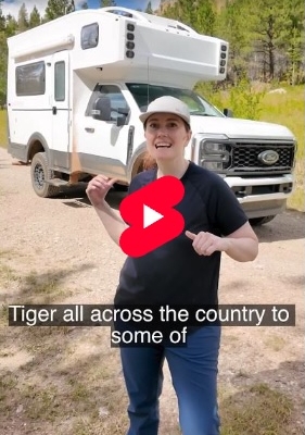 Video thumbnail for 'Introducing the Tiger Pant' with a woman in a cap standing in front of a white camper van in a grassy clearing; a red play button is centered on the image. Overlay text includes 'Introducing the Tiger Pant' and 'Tiger all across the country to some of'.